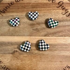 Five checkered heart beads are placed on a wooden board with the text "Annie and the Five Guys" engraved around the edge.