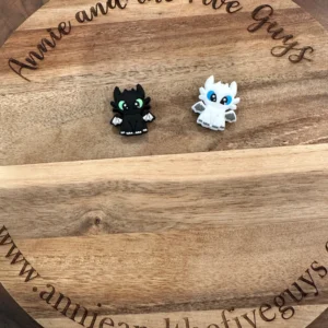 Two small Dragon figurines, one black and one white, are placed on a round wooden board with the text "Annie and the Five Guys" engraved around the edge.