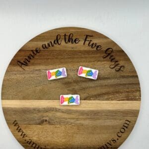 Wooden round board with the text "Annie and the Five Guys" and three "LF silicone focal bead" colorful candies on it. Website link "www.annieandthefiveguys.com" is also visible at the bottom of the board.