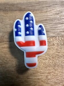 A small Eagle on US flag patriotic silicone focal bead placed on a wooden surface.