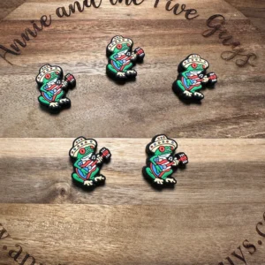 Five Puerto Rican coquí silicone focal beads featuring a frog playing an electric guitar on a wooden surface with the text "Annie and the Five Guys" and a website URL.