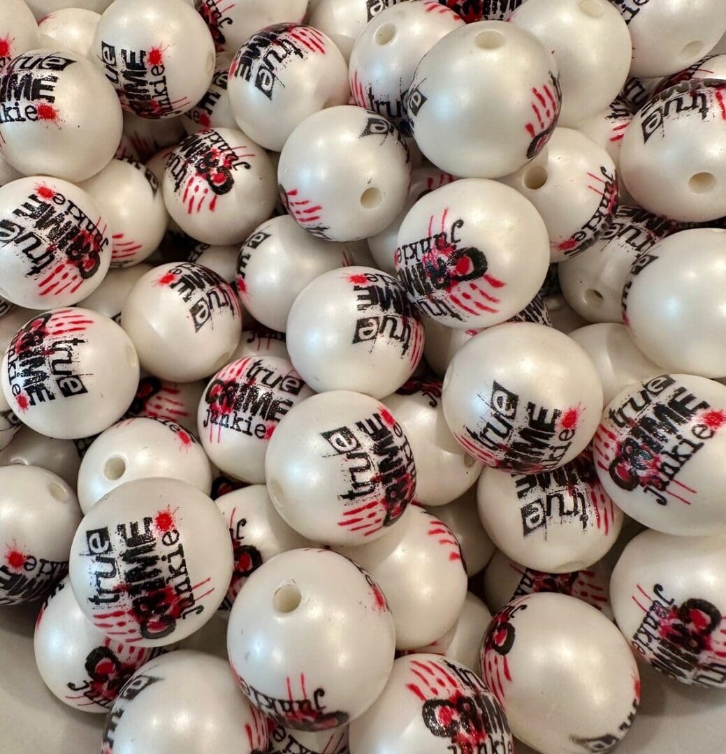 A pile of 20MM True Crime Junky Chunky Bubblegum Beads, 20MM candy bead, 20mm Bubble Gum Beads, 20mm Beads, 4 beads per pack branded with "true Aim" in black and red graffiti-style lettering, featuring a hole on each bead.