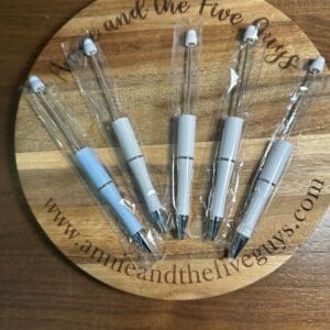 A round wooden plaque with the text "www.annieandthefiveguys.com" holds five UV Color changing pens. Beadable, each individually wrapped in plastic.