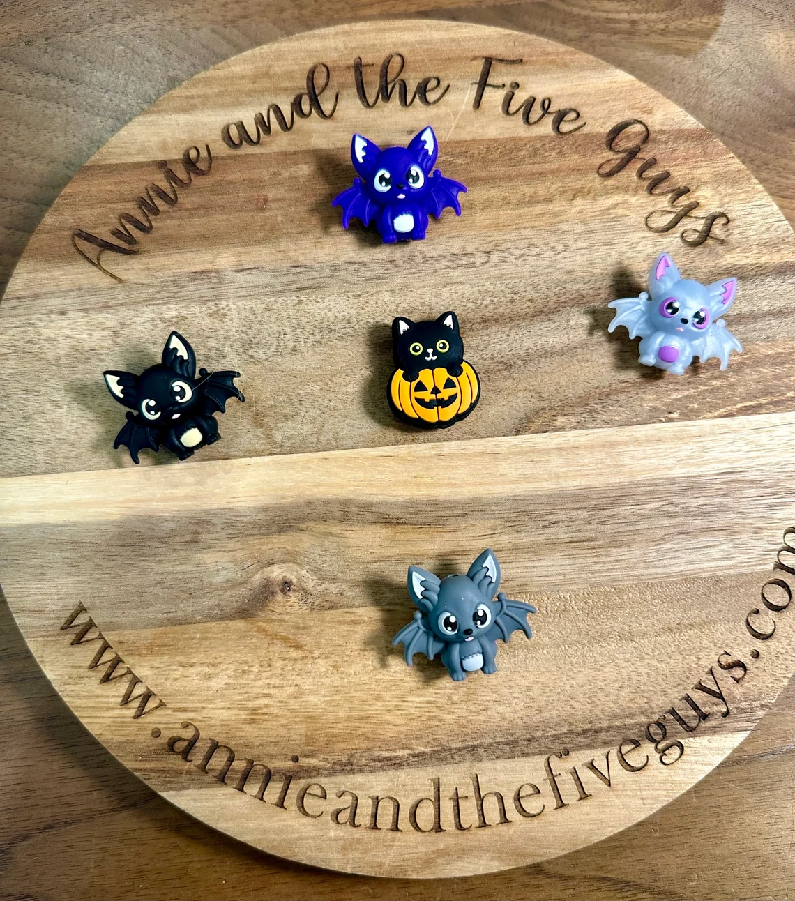 Small 3D bat or pumpkin cat silicone focal beads are arranged in a circle on a wooden display board with the text "Annie and the Five Guys" and the website "www.annieandthefiveguys.com".