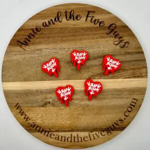 A circular wooden board with "Annie and the Five Guys" inscribed on the edge displays five red and white "Baby Bunny" pins. Website www.annieandthefiveguys.com is printed at the bottom.