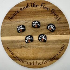 Five pins with the text "Livin' my Best Life" displayed on a round wooden board with the text "Annie and the Five Guys" around the edge.