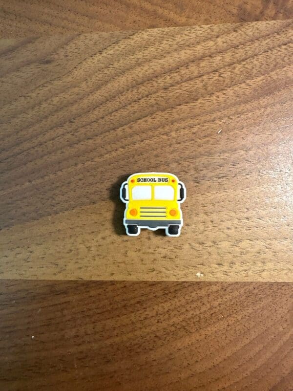 Small yellow school bus eraser on a wooden surface.