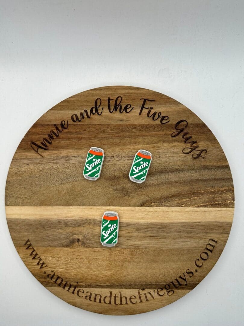 A round wooden plaque with the text "Annie and the Five Guys" and "www.annieandthefiveguys.com" features a White soda silicone focal bead.