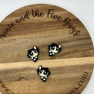 Three small character pins of Buttercup from The Powerpuff Girls placed on a round wooden board with text "anniceandthefiveguys.com" engraved around the edge.