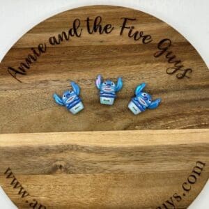 Three small, blue figurines with labels on a wooden tray that reads "Annie and the Five Guys" and has a web address at the bottom.