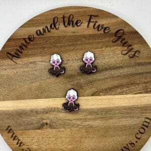 Three small pins featuring a character with white hair and purple skin are displayed on a wooden board with the text "Annie and the Five Guys.