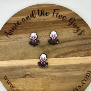 Three small pins featuring a character with white hair and purple skin are displayed on a wooden board with the text "Annie and the Five Guys.