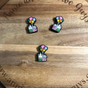 Three colorful Balloon house silicone focal beads are arranged on a wooden surface with the text "Annie and the Five Guys" engraved on it.