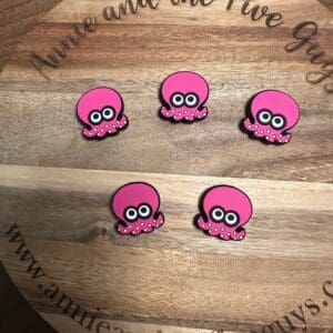 Five pink octopus-shaped magnets are arranged on a circular wooden board with the text "Annie and the Five Guys" and the website "www.annieandthefiveguys.com" engraved around the edge.