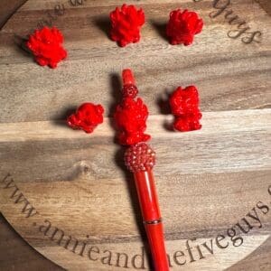 A round wooden board with text and six red figurines surrounding a red and gold pen.