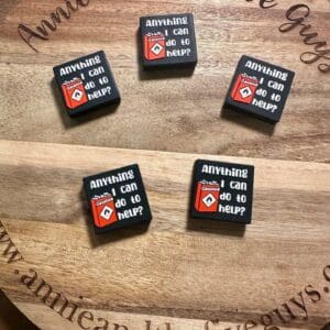 Five square pins display the phrase "Anything I can do to help?" with a red diamond logo on a wooden board that says "Annie and the Five Guys.