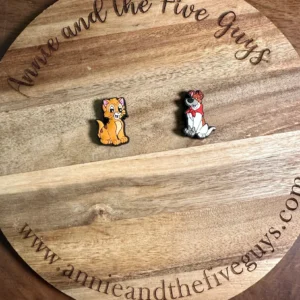 Two cat or dog silicone focal beads on a round wooden board that has the text "Annie and the Five Guys" and "www.annieandthefiveguys.com" engraved on it.