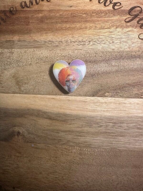 Heart-shaped pin with an African American, African queens silicone focal beads against a wooden background.