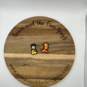 A wooden board with text "Orange Cat and Yellow Dog Silicone Focal Bead" circularly engraved on the edge, featuring two small cartoon character pins.