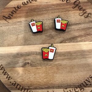 Three Fast food fries silicone focal beads depicting French fries and a soda with McDonald's logos are displayed on a wooden plaque that reads "Annie and the Five Guys" and includes a related website URL.