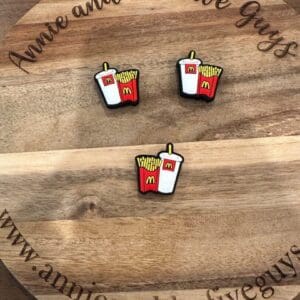 Three Fast food fries silicone focal beads depicting French fries and a soda with McDonald's logos are displayed on a wooden plaque that reads "Annie and the Five Guys" and includes a related website URL.