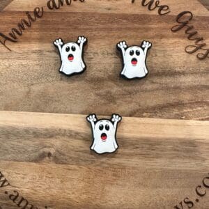 Three ghost-shaped cookies with raised arms, white frosting, and red mouths are arranged on a wooden board with the words "Annie and the Five Guys" engraved on it.