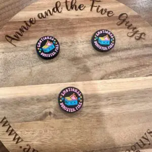 Three circular pins with "EMOTIONAL DUMPSTER FIRE" text and a graphic of a dumpster fire set on a wooden surface with "Annie and the Five Guys" text around the edge.

Replaced: Three Emotional Dumpster Fire silicone focal beads set on a wooden surface with "Annie and the Five Guys" text around the edge.