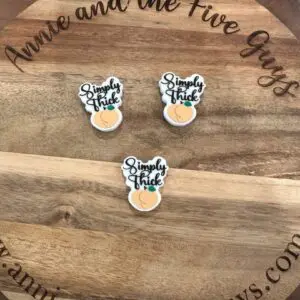 Three "Simply thick silicone focal bead" branded items are placed on a wooden surface featuring the website "annieandthefiveguys.com" and the text "Annie and the Five Guys" around the edge.