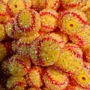 A pile of small, yellow beaded balls decorated with iridescent sequins and red thread detailing.