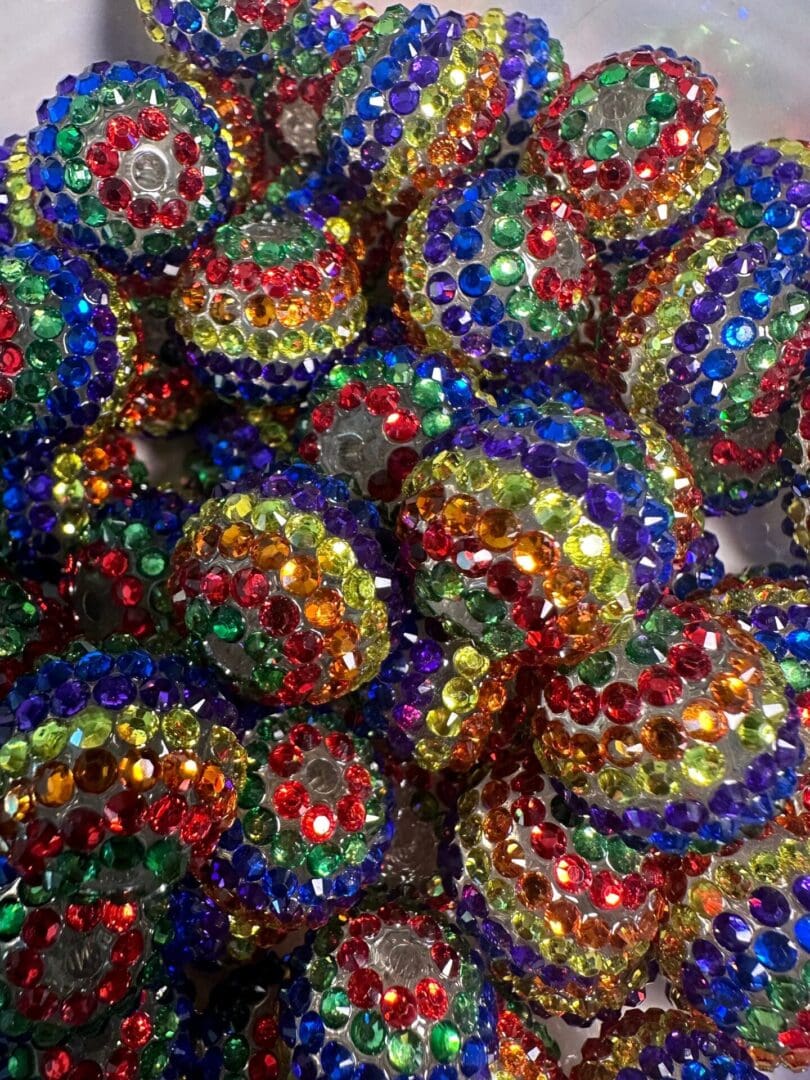 A collection of round beads covered in multicolored rhinestones, including red, blue, green, yellow, and purple.