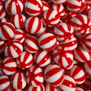 A close-up of numerous red and white striped round beads, resembling peppermint candies, piled together.