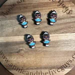 Four Princess T silicone focal beads of a girl with a tiara and blue dress on a circular wooden board with "Annie and the Five Guys" written around the edge.