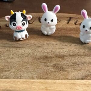 Small 3d cows or bunnies placed in a semicircle on a wooden surface.