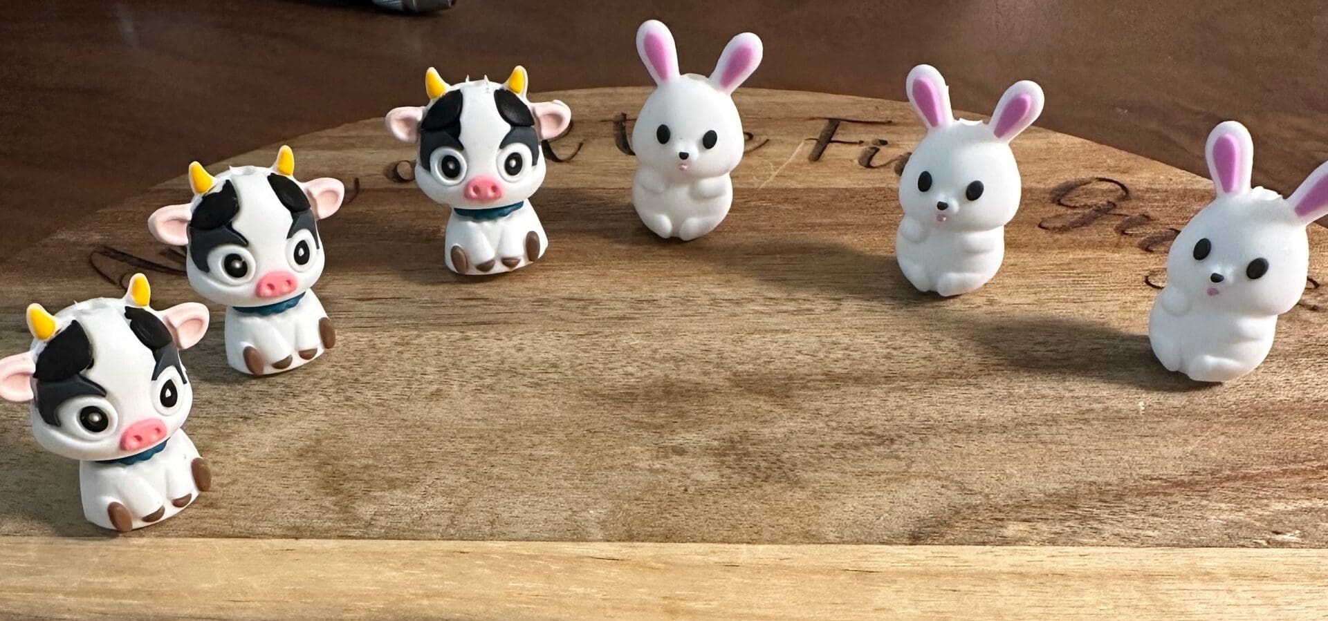 Small 3d cows or bunnies placed in a semicircle on a wooden surface.