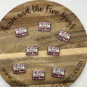 Never Underestimate a single mom silicone focal bead. Custom Collab with eight pins that read "Never underestimate a single mom" arranged in a circular pattern. The bead has the text "Annie and the Five Guys" written around it.