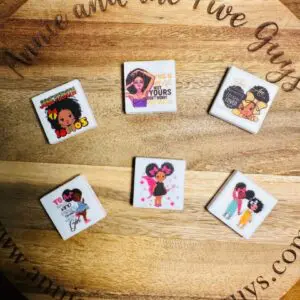 Six African American girl, women, Juneteenth silicone focal beads are displayed on a wooden surface with the website "annieandthefiveguys.com" faintly visible in the background.