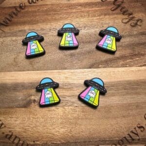 Five colorful Alien ghost ufo silicone focal beads featuring cartoon UFOs beaming up a ghost, arranged on a wooden board with text "annieandthefiveguys" at the bottom.