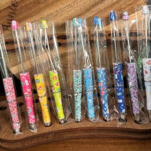 A row of colorful, patterned Beadable pens with nursing, doctor, healthcare print wrapped in plastic packaging displayed on a wooden surface.