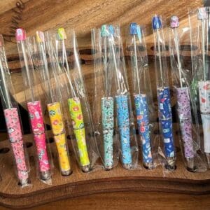 A row of colorful, patterned Beadable pens with nursing, doctor, healthcare print wrapped in plastic packaging displayed on a wooden surface.