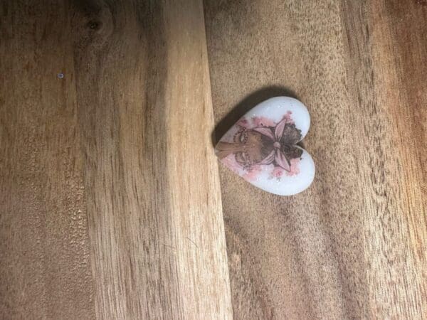 African American, African queens silicone focal beads with a floral design and portrait in the center, resting on a wooden surface with a visible seam.