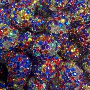 A close-up image of numerous decorative balls covered in colorful, multi-faceted gems in various shades of blue, red, green, yellow, and purple.