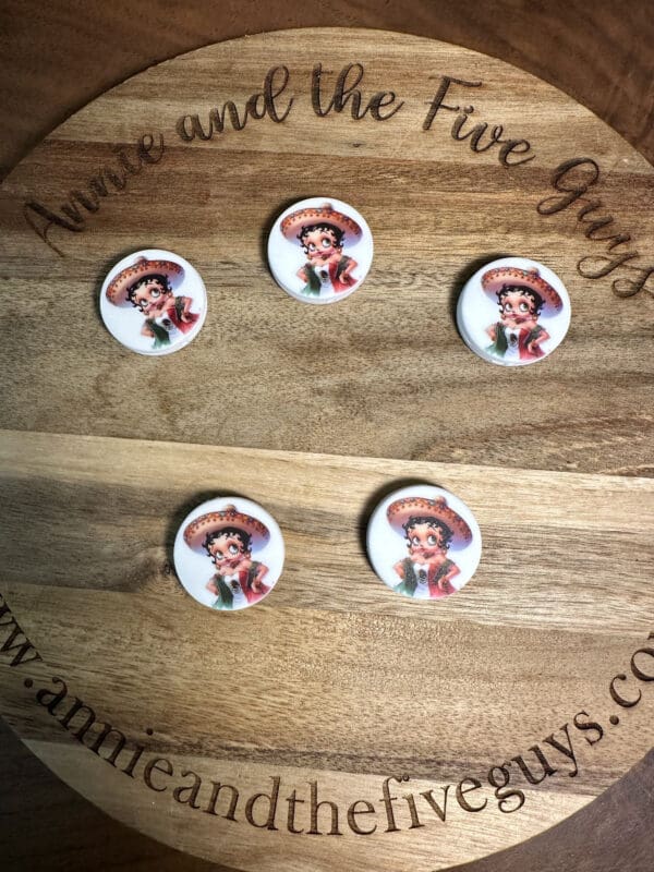 Five Betty Boop silicone focal beads, multicultural, are displayed on a wooden board. The board is engraved with the text, "Annie and the Five Guys" and the website "annieandthefiveguys.com.