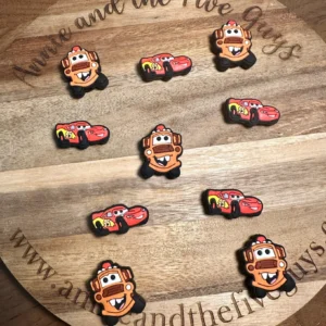 Colorful cartoon truck or car silicone focal beads arranged on a wooden board with "Annie and the Five Guys" written on it.