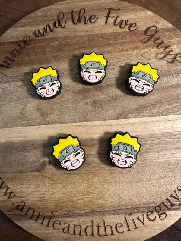 Four pins featuring an animated character's face with yellow hair and a headband on a wooden surface with text "Annie and the Five Guys".