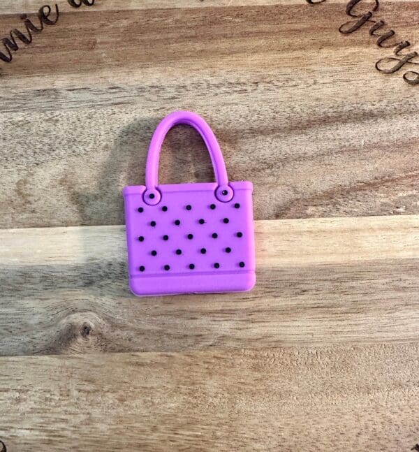 A small purple 3D bag with black dots is placed on a wooden surface.