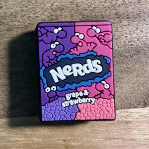 A Nerds candy container labeled "grape & strawberry," featuring a playful design of cartoon characters on a wooden surface.