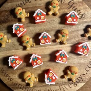 3D gingerbread man and house silicone focal beads displayed on a wooden platter.