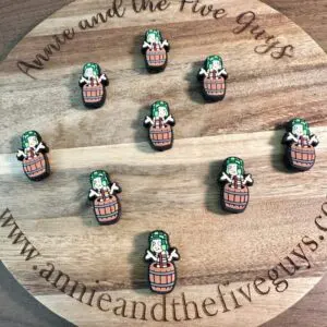 A circular wooden board with the text “Annie and the Five Guys” showcases nine El Chavo Silicone focal beads, depicting a character in a barrel with a green hat. The website www.annieandthefiveguys.com is also visible.