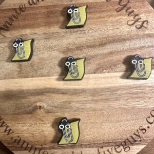 A round wooden board featuring five Paperclip and Paper silicone focal beads, each depicting a yellow cartoon character with glasses, and engraved with the text "annieandthefiveguys.com.