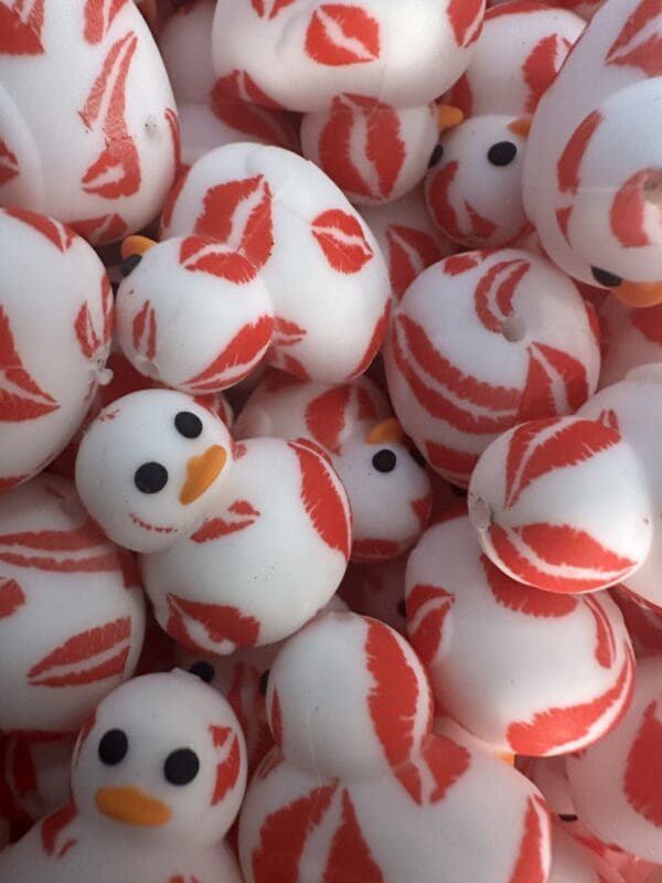 A pile of rubber ducks, white with orange beaks and black eyes, covered in red lip print patterns.